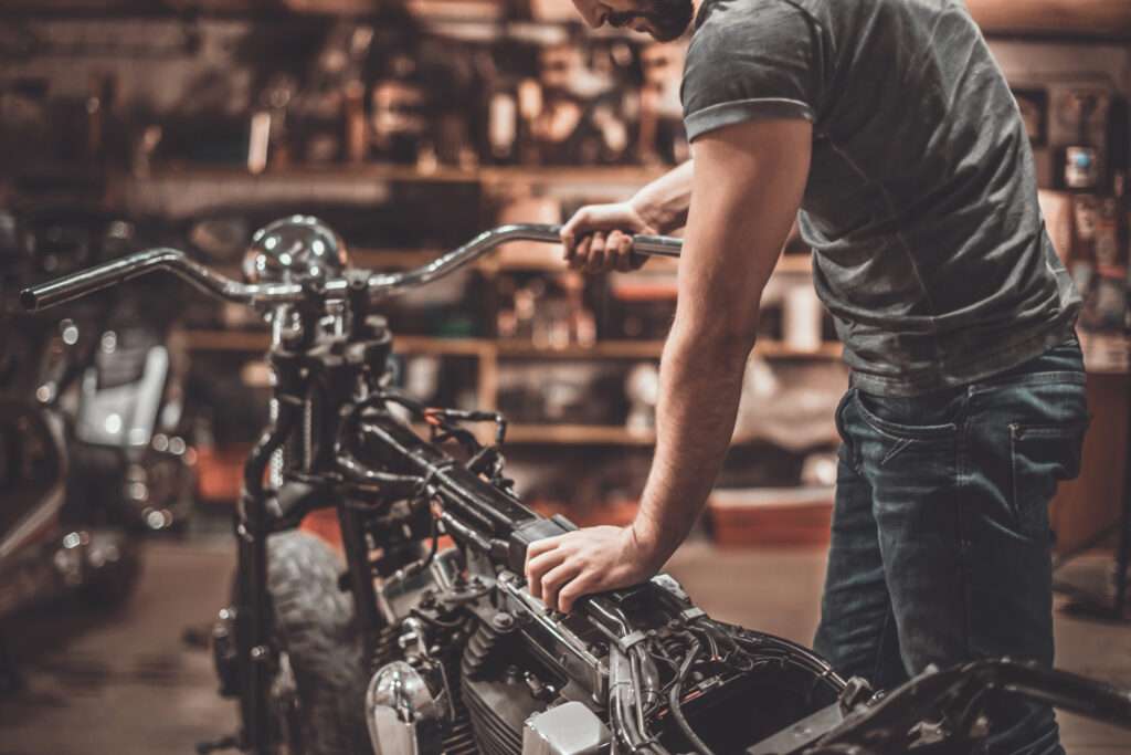 Man examining motorcycle. Close-up of young man examining motorcycle in repair shop